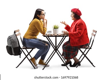 Full length profile shot of a young and senior woman sitting in a cafe and talking isolated on white background - Powered by Shutterstock