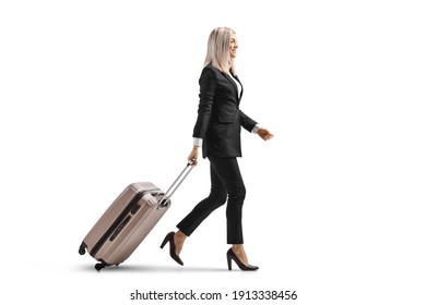 Full length profile shot of a young businesswoman walking and pulling a suitcase isolated on white background