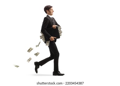 Full length profile shot of a young businessman walking with a briefcase and money falling behind isolated on white background