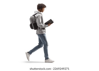 Full length profile shot of a young african american man walking and reading a book isolated on white background - Powered by Shutterstock