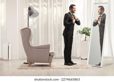 Full length profile shot of a young elegant man getting ready in front of a mirror at home - Powered by Shutterstock