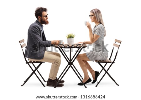 Full length profile shot of a young man and woman drinking coffee at a table isolated on white background