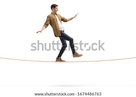 Full length profile shot of a young man walking on a rope isolated on white background