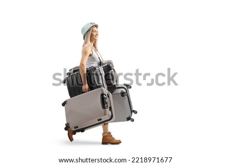 Full length profile shot of a young woman walking and carrying many suitcases isolated on white background