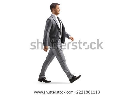 Full length profile shot of a young professional man in a gray suit walking isolated on white background