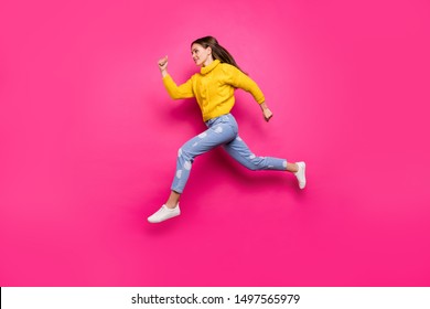 Larga foto de perfil de jóvenes concentrados saltando corriendo velozmente adelante usando jeans con poros de denim amarillos aislados sobre fondo fuchsia