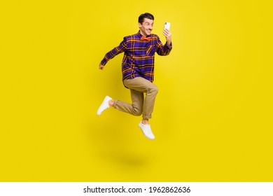 Full length profile side photo of young man happy positive smile jump up make selfie cellphone isolated over yellow color background - Shutterstock ID 1962862636