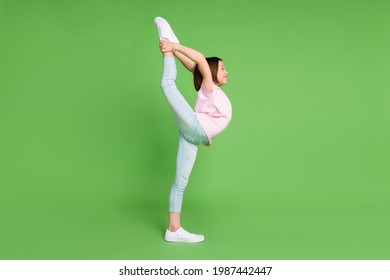 Full length profile side photo of young little girl hold leg stretching flexible sportive isolated over green color background