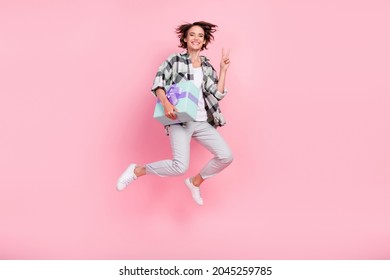 Full Length Profile Side Photo Of Young Woman Happy Smile Jump Hold Present Box Show V-sign Isolated Over Pink Color Background