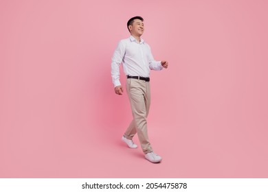 Full length profile side photo of young asian man go walk step look empty space isolated over pink color background - Shutterstock ID 2054475878