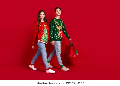 Full length profile side photo of romantic charming wife husband move empty space market choose xmas tree isolated on red color background