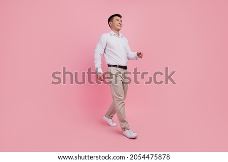 Full length profile side photo of young asian man go walk step look empty space isolated over pink color background Stock photo © 