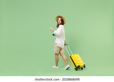 Full Length Rear Back View Traveler Tourist Woman In Casual Clothes Hat Hold Suitcase Go Show Thumb Up Isolated On Green Background. Passenger Travel Abroad Weekend Getaway. Air Flight Journey Concept