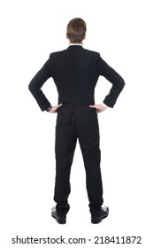 Full length rear view of confident businessman standing with hands on hips over white background