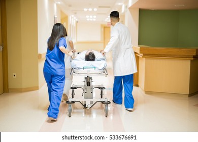 Full length rear view of a group of doctors transporting a patient in a stretcher