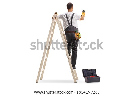 Full length rear view shot of a repairman on a ladder drilling with a machine into a wall isolated on white background