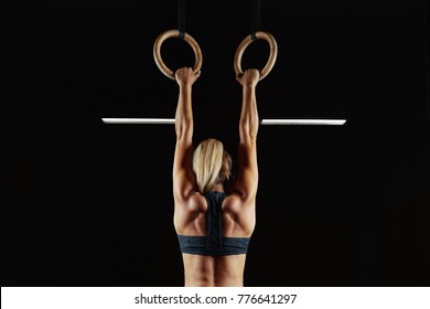 Full length rearview shot of a female athlete performing pull-ups on gymnastic rings. Fitness and crossfit woman with strong beautiful body exercising on gym rings health power endurance competitive - Powered by Shutterstock