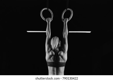 Full length rearview shot of a female athlete performing pull-ups on gymnastic rings. Fitness woman with strong beautiful body exercising on gym rings health power endurance competitive - Powered by Shutterstock