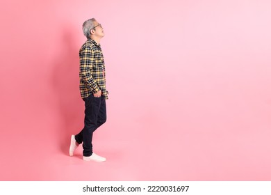 The full length of senior Asian man standing on the pink background. - Shutterstock ID 2220031697