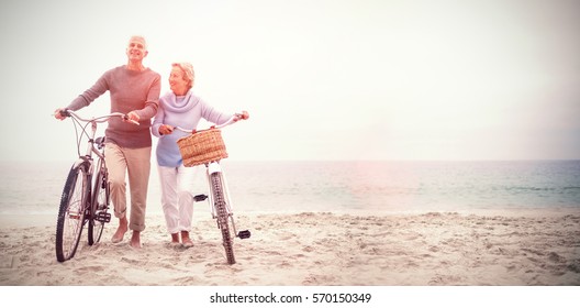 Full length of senior couple with their bicycles at the beach - Shutterstock ID 570150349
