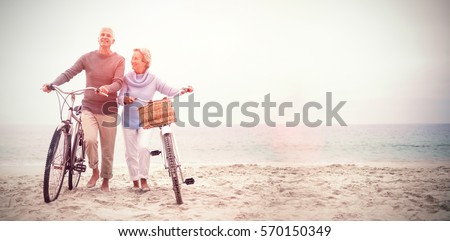 Full length of senior couple with their bicycles at the beach
