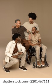 Full length shot of an African American man in his 40's using a wheelchair, a biracial man in his 30's, a Liberian American man in his 20's, and a multiracial man in his 50's laughing together. Stock Photo