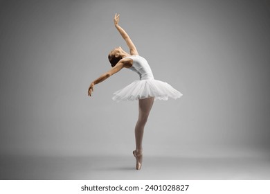 Full length shot of a ballerina dancing and leaning backwards isolated on gray background
