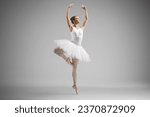 Full length shot of a ballerina in a white dress dancing isolated on gray background