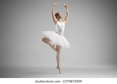 Full length shot of a ballerina in a white dress dancing isolated on gray background