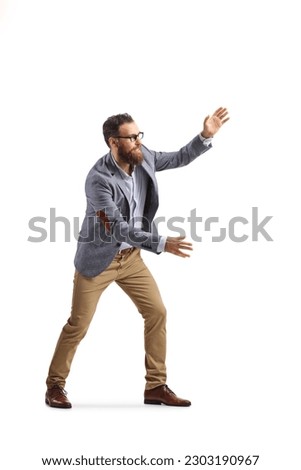 Full length shot of a cheerful bearded man trying to catch something isolated on white background