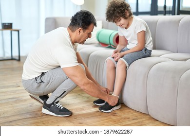 Full Length Shot Of Dad Tying The Laces On A Child Sneakers While Getting Ready For Workout At Home