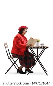 Full Length Shot Of An Elderly Lady At A Cafe Table Reading A Book Isolated On White Background