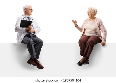 Full Length Shot Of An Elderly Woman Talking To A Mature Doctor And Sitting On A Blank Panel Isolated On White Background