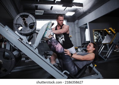 Full Length Shot Of A Female Athlete Exercising On Leg Press Gym Machine With Her Personal Trainer