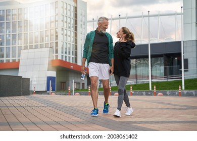 Full Length Shot Of Happy Sportive Middle Aged Couple In Sportswear Looking Cheerful While Walking Together Outdoors After Workout