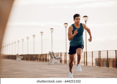 Full length shot of healthy young man running on the promenade. Male runner sprinting outdoors. - Shutterstock ID 644251102