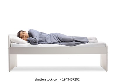 Full length shot of a man sleeping peacefully in a single bed isolated on white background