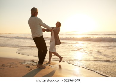 Full Length Shot Of Romantic Senior Couple Enjoying A Day At The Beach. Mature Couple Enjoying Their Vacation On The Beach.