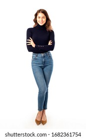 Full length shot of smiling young woman wearing turtlenck sweater and blue jeansi while standing at isolated white background. 