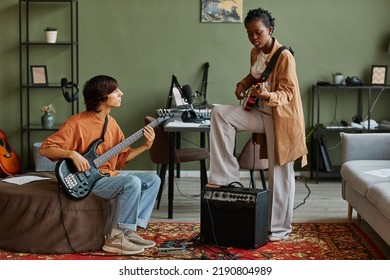 Full length shot of two young musicians playing guitars together while composing songs in cozy studio - Powered by Shutterstock