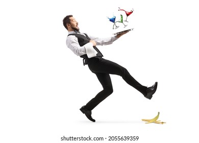 Full length shot of a waiter slipping on a banana peel and falling with a tray of coctails isolated on white background