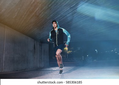 Full length shot of young athlete running under bridge in city. Fit young man jogging in the city. - Powered by Shutterstock