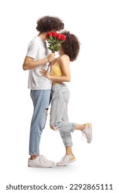Largo disparo de una pareja joven besándose y escondiéndose detrás de un montón de rosas rojas aisladas en fondo blanco