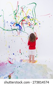 Full Length Shot Of A Young Little Kid Painting Something Abstract On White Big Wall Using Different Colors.