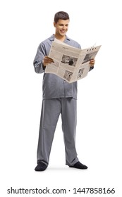 Full Length Shot Of A Young Man In Pyjamas Standing And Reading A Newspaper Isolated On White Background