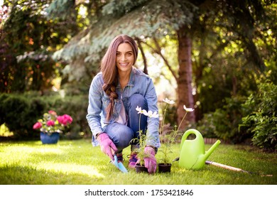 Full Length Shot Of Young Woman Gardening At Home In The Backyard. Happy Woman Wearing Casual Clothes While Planting Flowers.