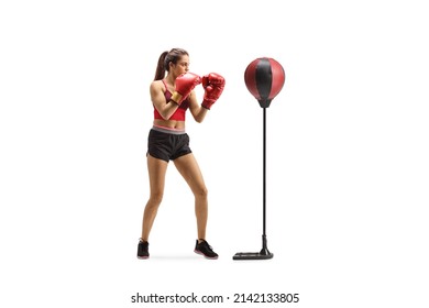 Full length shot of a young woman punching a free standing boxing bag isolated on white background