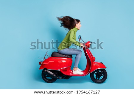 Full length side photo photo portrait of excited girl driving red scooter isolated on pastel blue colored background
