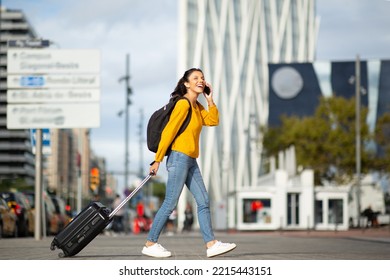 Full length side portrait happy young woman walking and talking with cellphone and bag - Shutterstock ID 2215443151