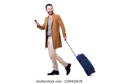 Full length side portrait of man walking with mobile phone and suitcase